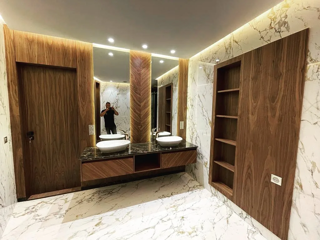 Salle de bain avec porte en noyer, niche en bois et murs en marbre