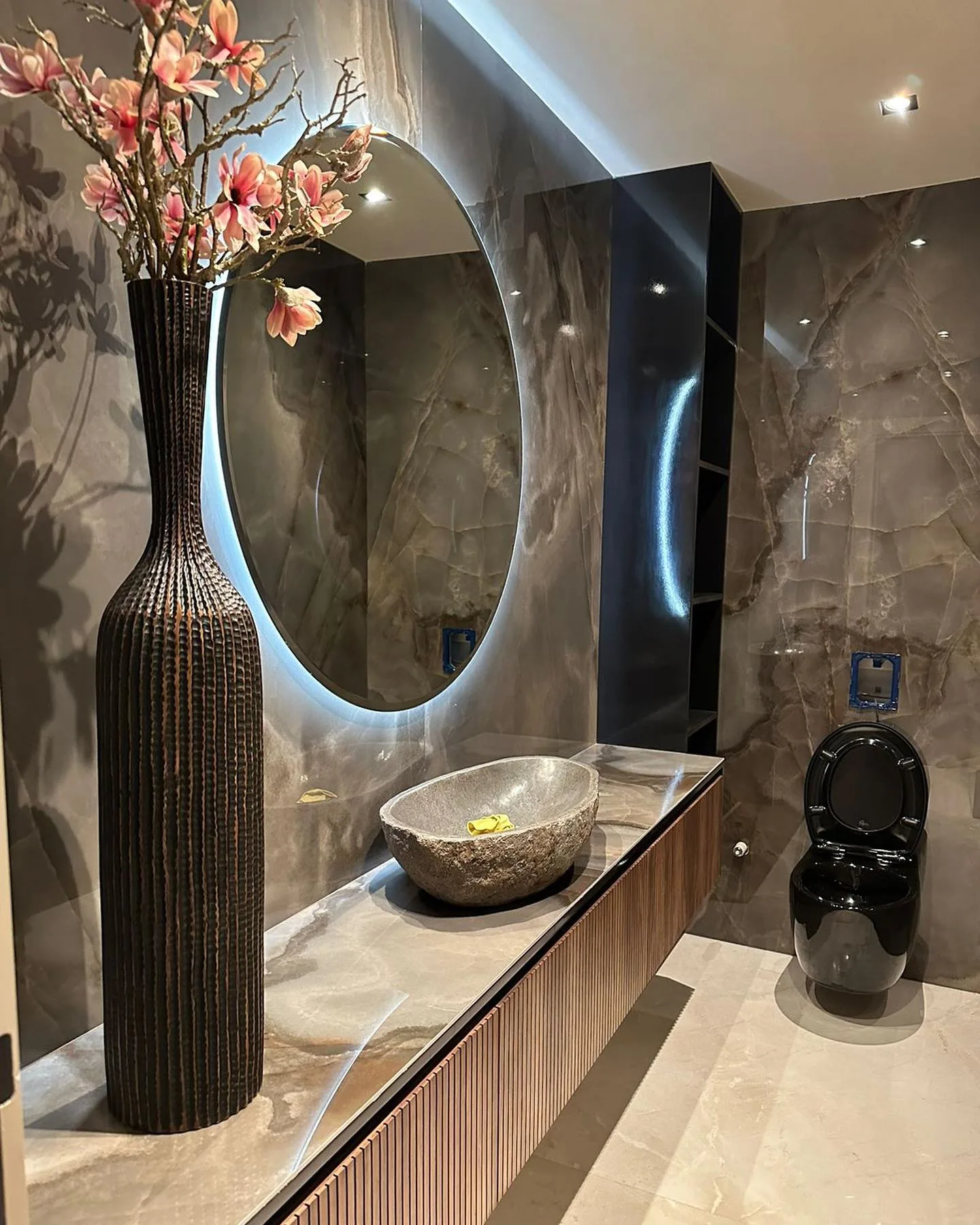 Meuble vasque en bois cannelé avec vasque en pierre et miroir rond éclairé